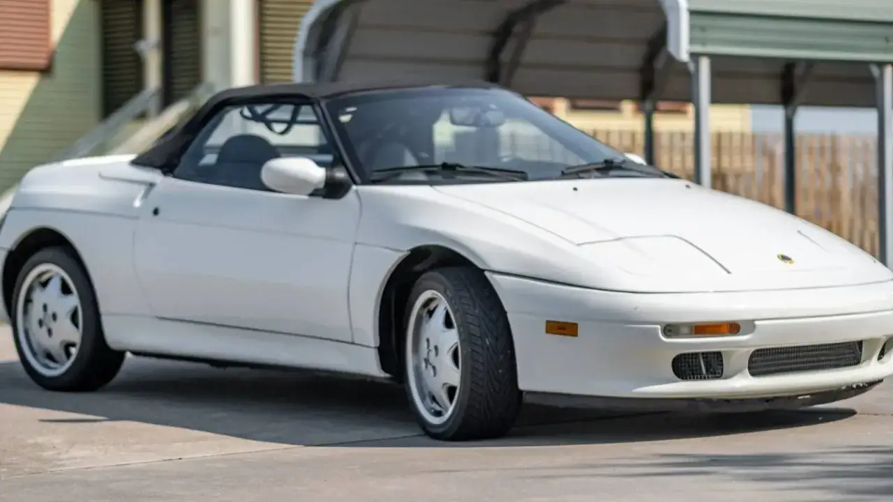 Vit Lotus Elan M100 cabriolet parkerad utomhus. En klassisk sportbil med en tidlös design.