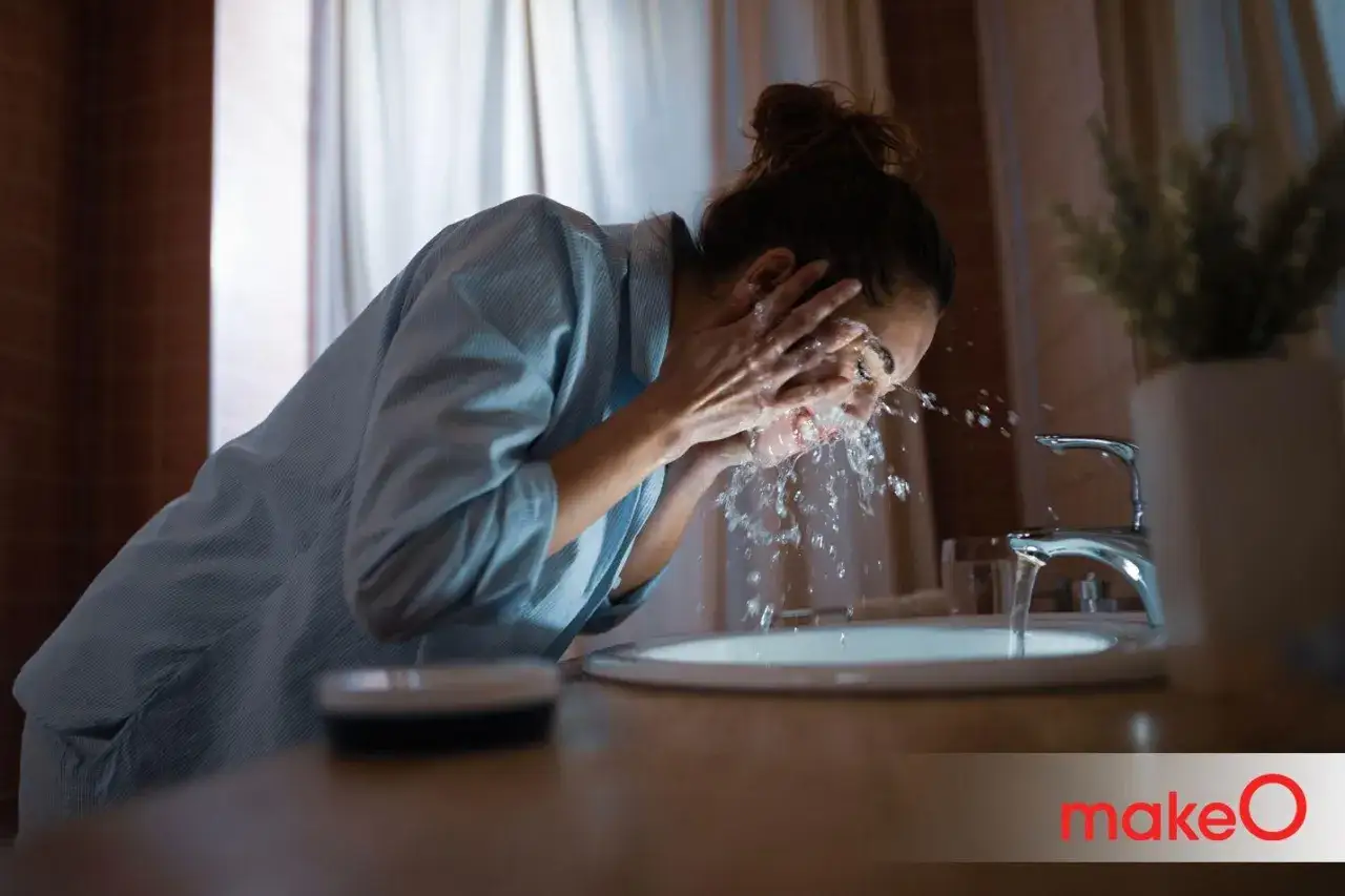 Mujer se lava la cara con agua fría en el baño, despertando sus sentidos.
