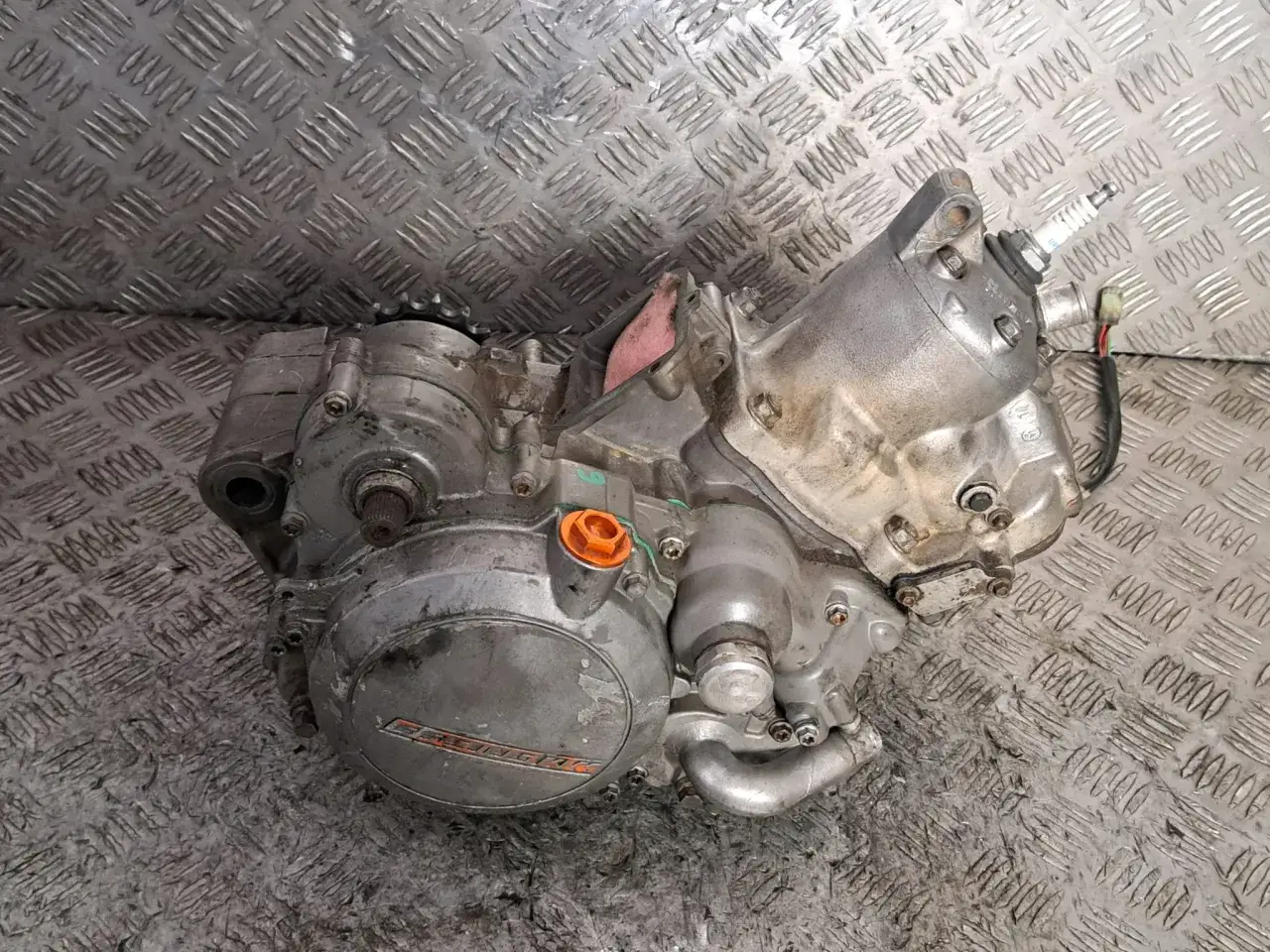 Silnik Husqvarna 125, gotowy do montażu. Widoczna świeca zapłonowa i elementy obudowy.