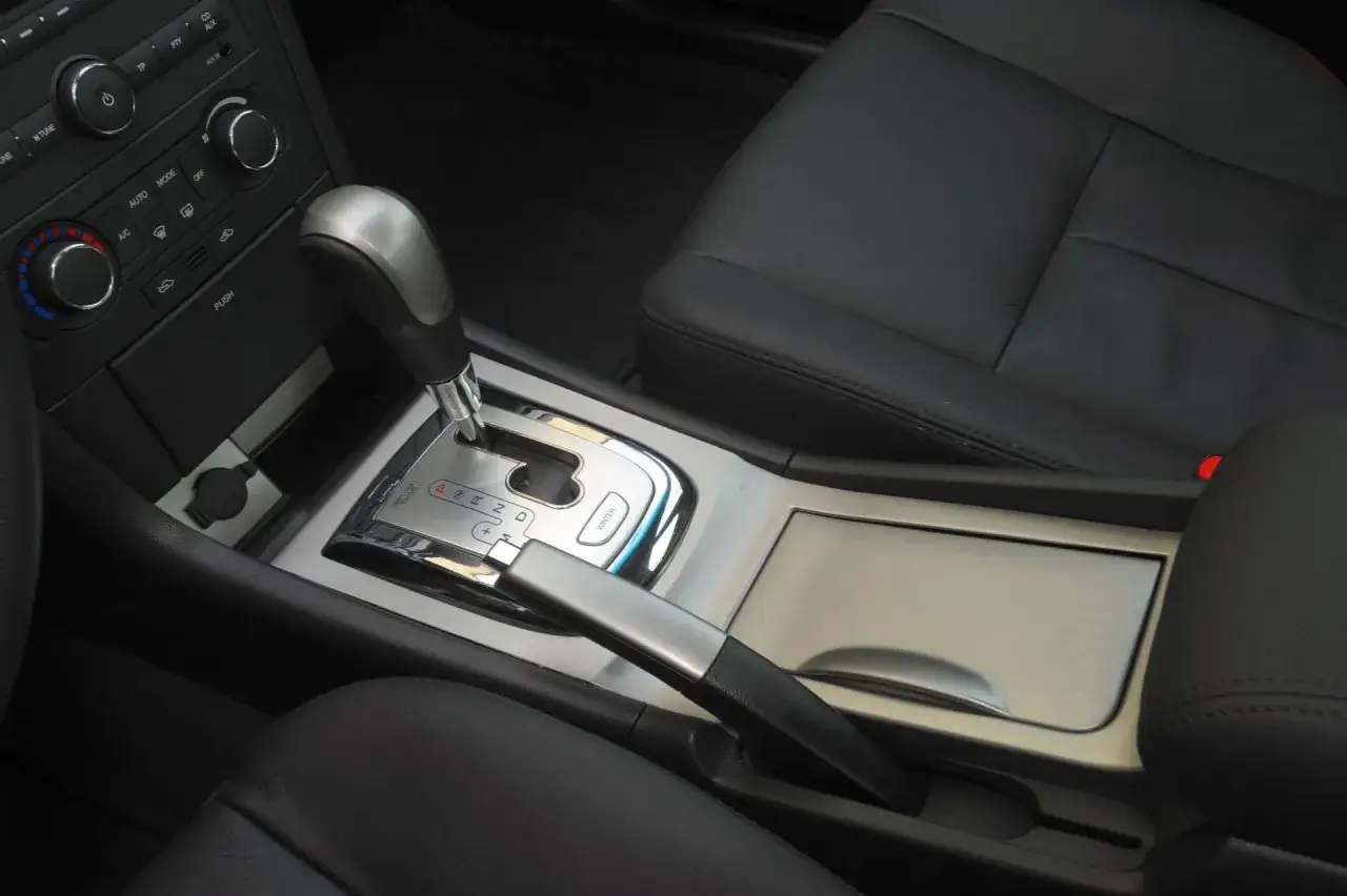 Wnętrze Chevrolet Epica 2007: dźwignia zmiany bieg&oacute;w, hamulec ręczny i panel sterowania klimatyzacją.