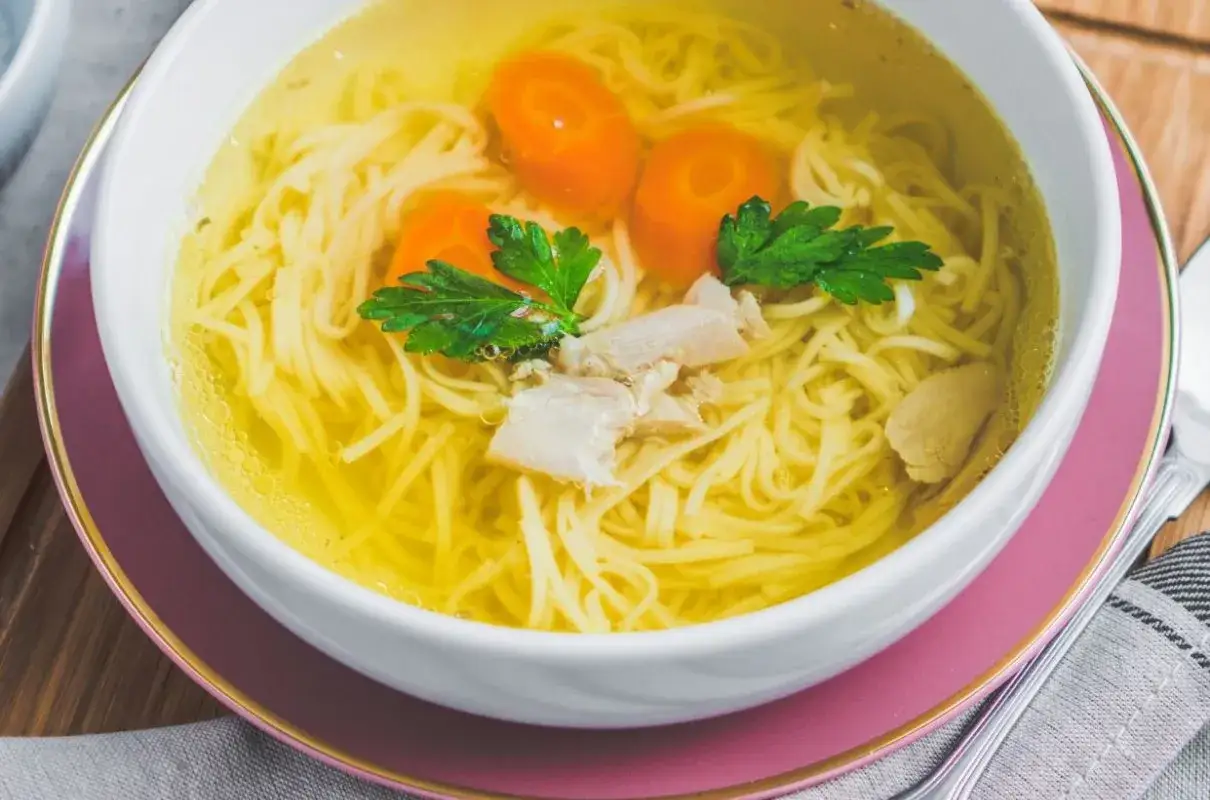 Aromaticzny rosół z makaronem, kawałkami kurczaka i marchewką, jak z przepisu Magdy Gessler. Idealny na chłodne dni.