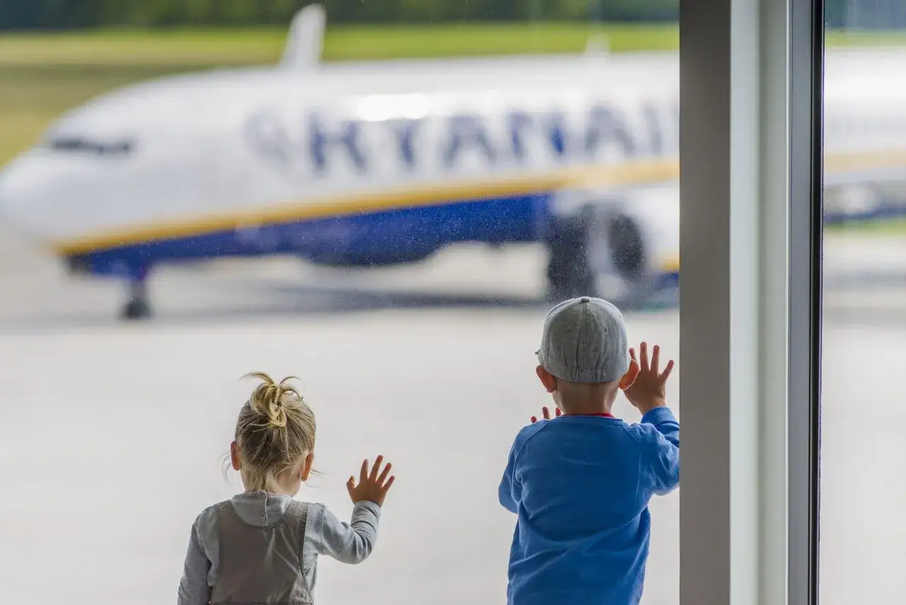 Dzieci patrzą na samolot Ryanair, zastanawiając się, ile trwa lot do Albanii z Wrocławia.