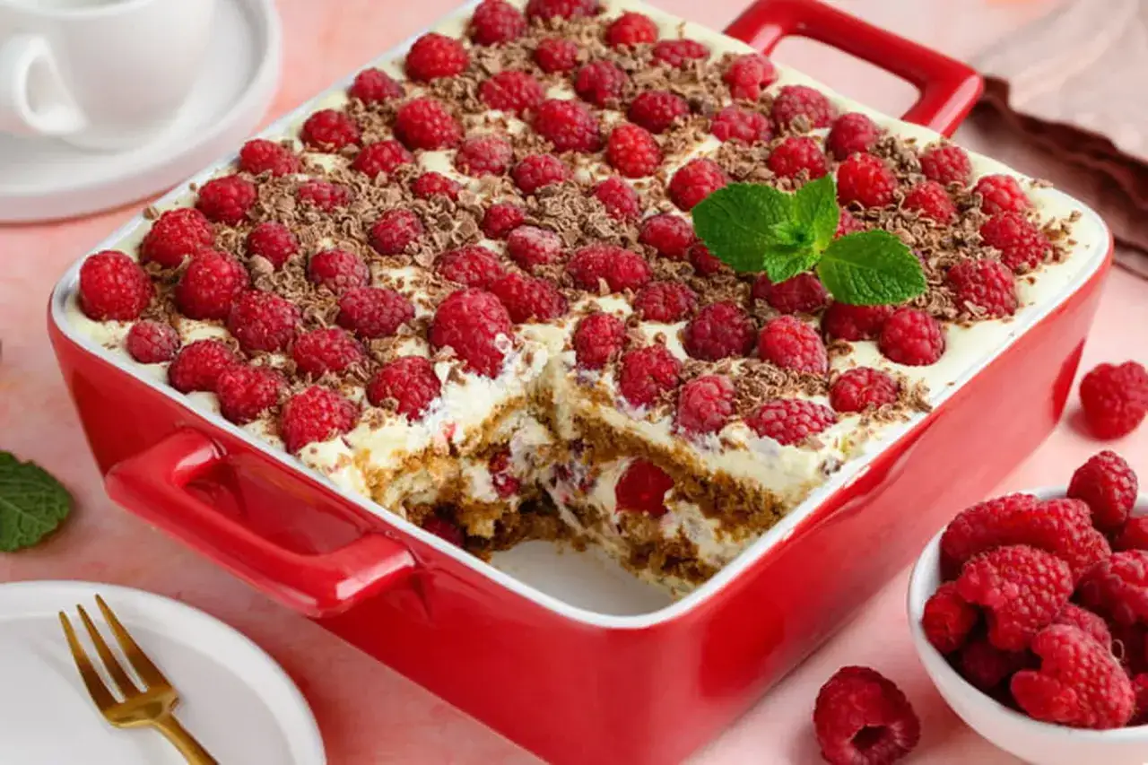 Un délicieux tiramisu framboise garni de fruits rouges frais et de copeaux de chocolat, prêt à être dégusté.