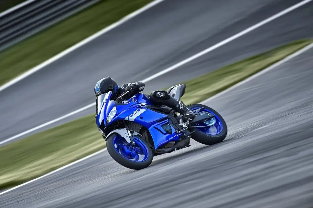 Motociclista in piega su una Yamaha R3 blu su pista. Il suo peso &egrave; ben bilanciato, agile e veloce.