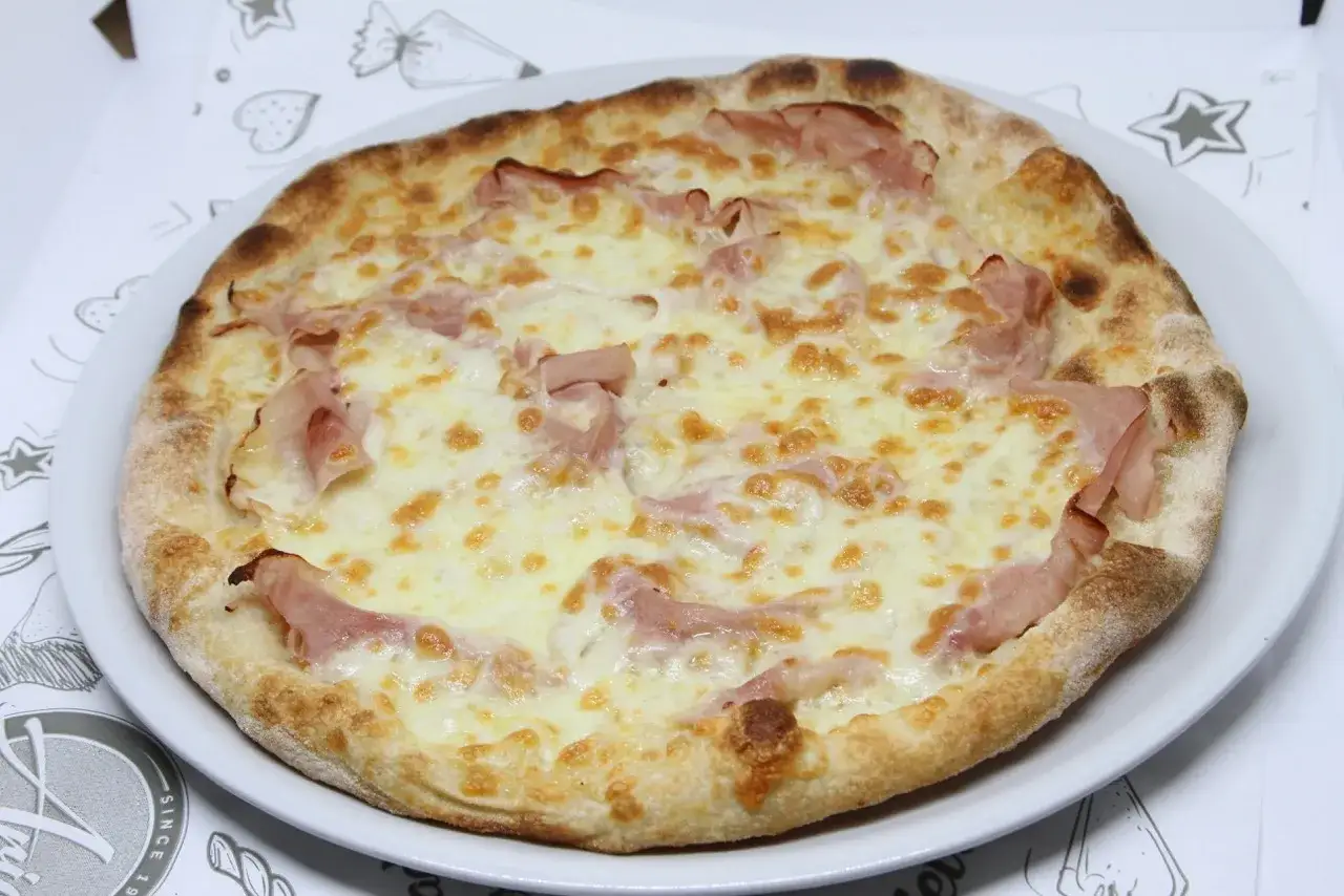 Pyszna pizza z szynką i serem, idealna na kolację. Zastanawiasz się, ile kcal ma pizza 32 cm? Ta wygląda na około 1200 kcal.