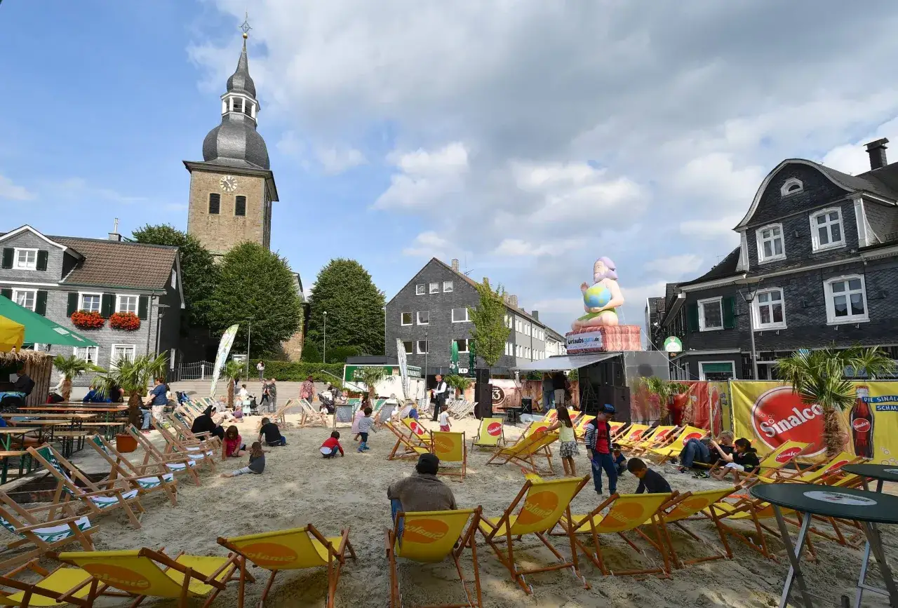 Strandfeeling in Radevormwald: Liegest&uuml;hle, Kinder spielen im Sand, eine riesige aufblasbare Figur und eine B&uuml;hne deuten auf spannende Radevormwald Veranstaltungen hin.