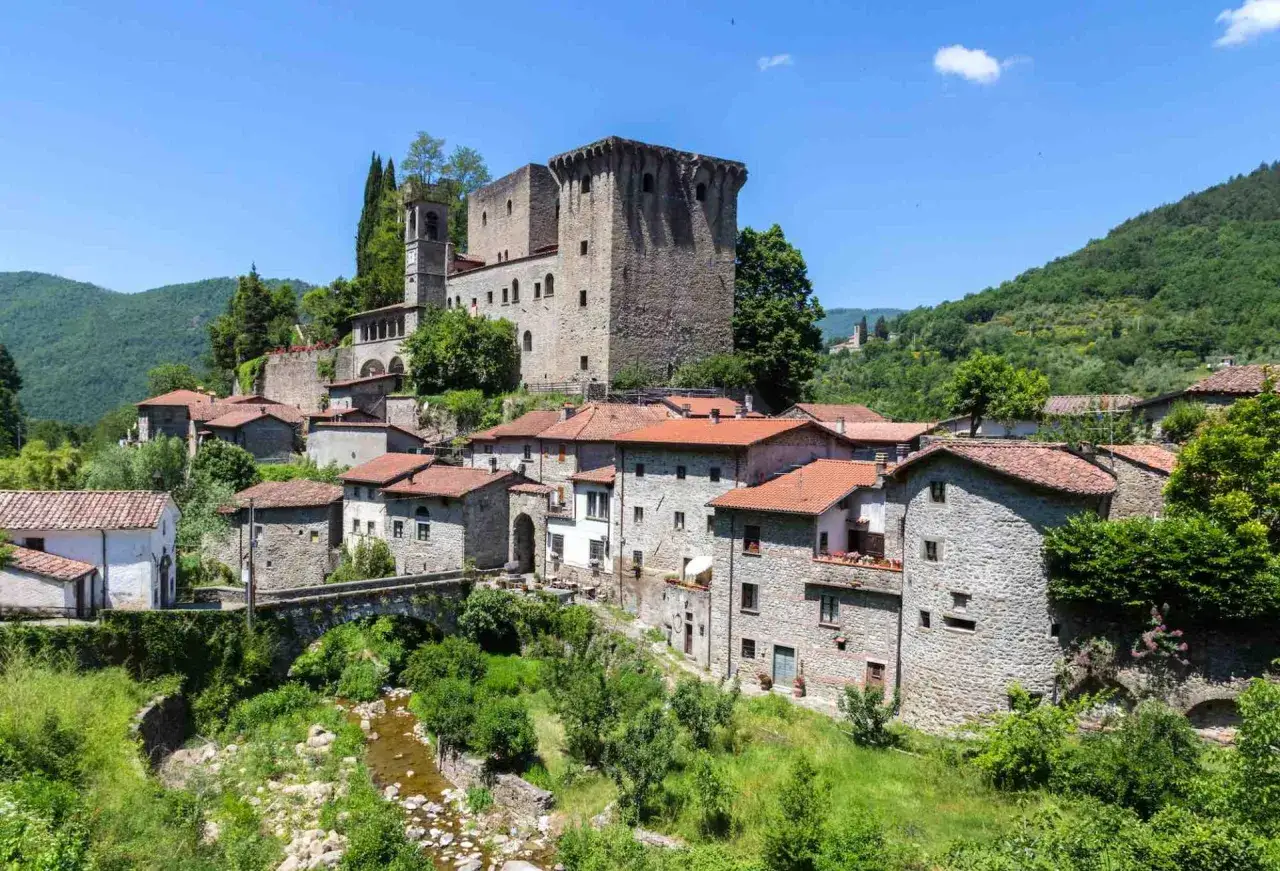 Fivizzano cosa vedere: borgo medievale con castello, case in pietra e un ponte su un ruscello.
