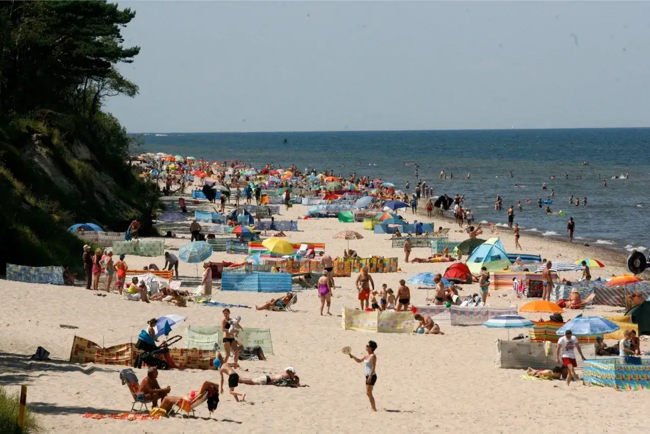 Tłum ludzi na plaży, szukających odpowiedzi, gdzie najbliżej nad morze z Wrocławia. Słońce, piasek i woda.