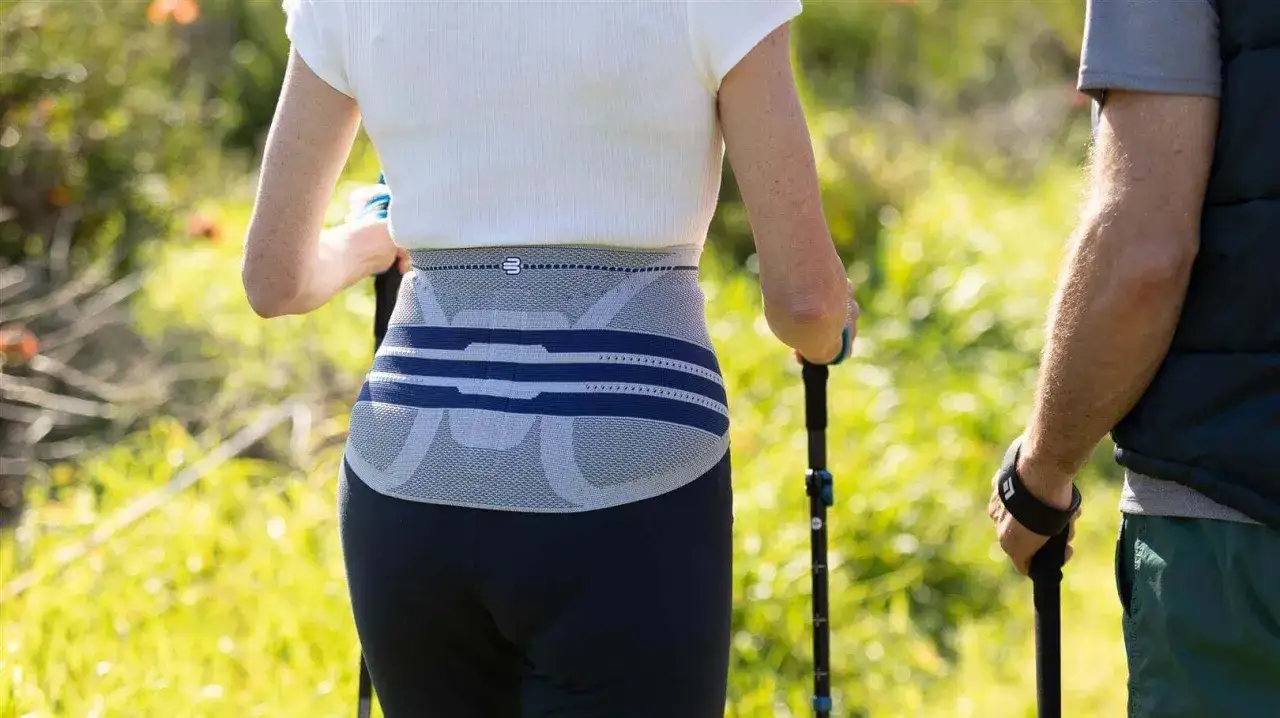 Frau mit R&uuml;ckenbandage beim Nordic Walking, unterst&uuml;tzt bei Bandscheibenvorfall.