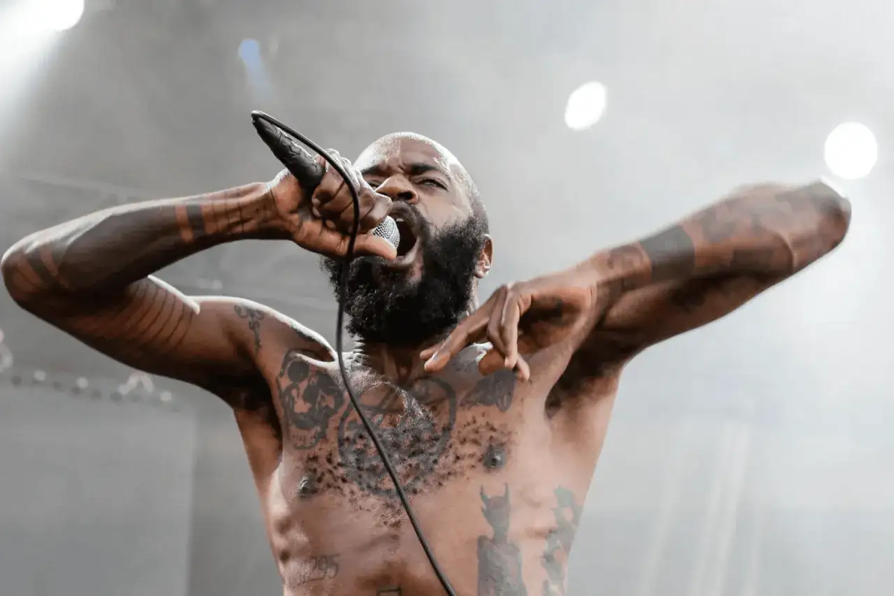 Un rappeur tatoué hurle dans un micro, bras levés. Une image puissante pour le marketing musical.