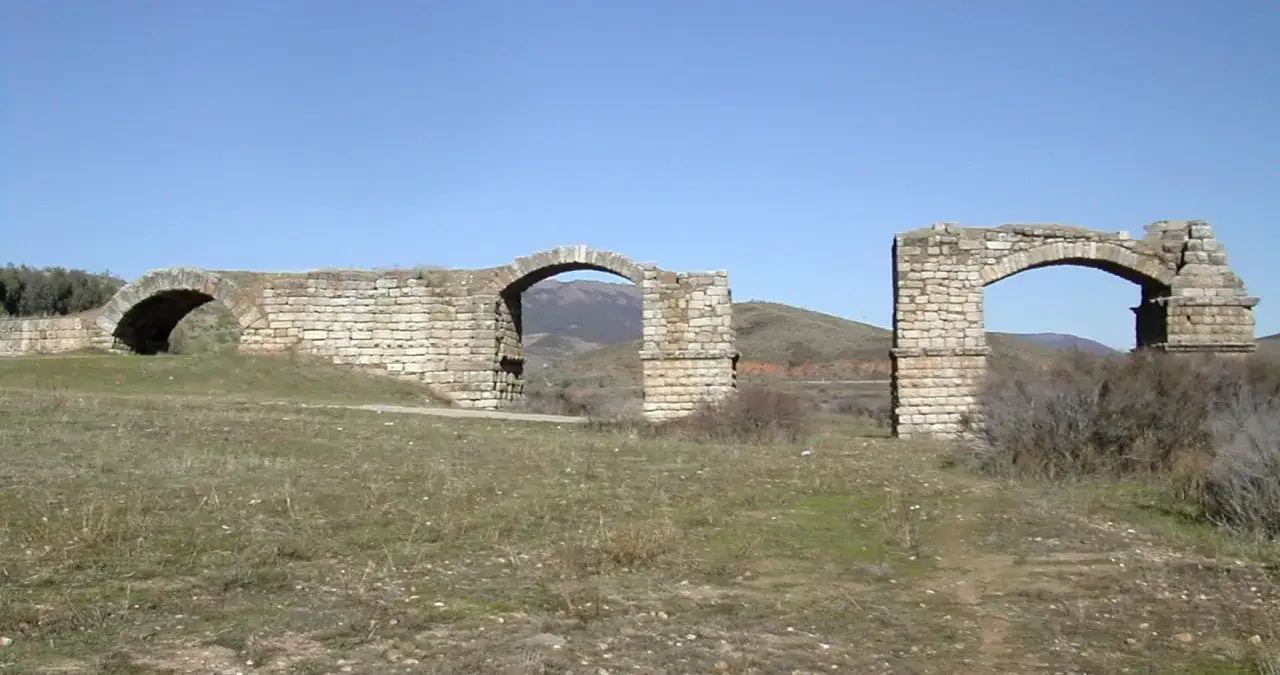 Ruinas del puente de Alconetar, con sus arcos de piedra y el paisaje montañoso al fondo.