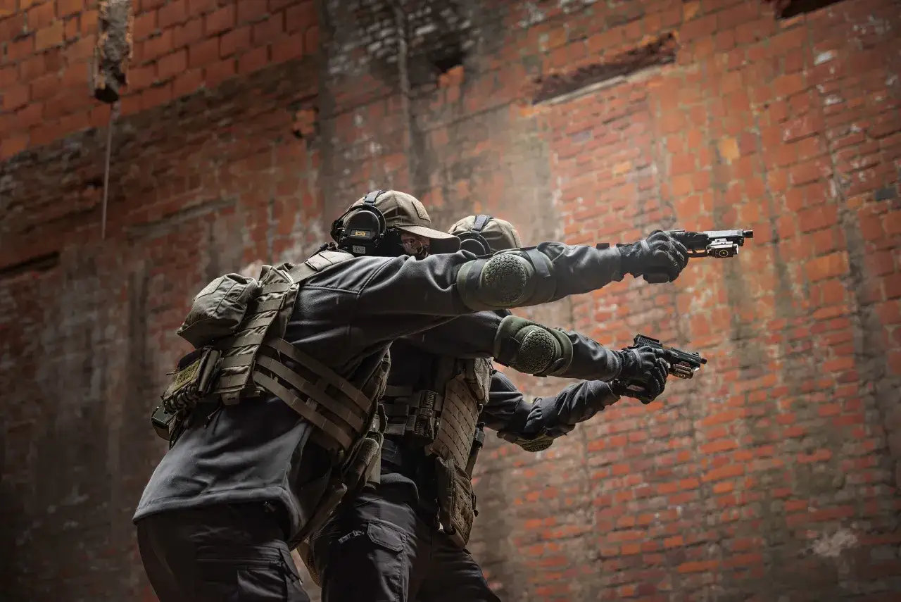 Dwóch graczy w taktycznym ekwipunku ćwiczy strzelanie z pistoletów, jakby wykonywali komendy na bronie CS GO.