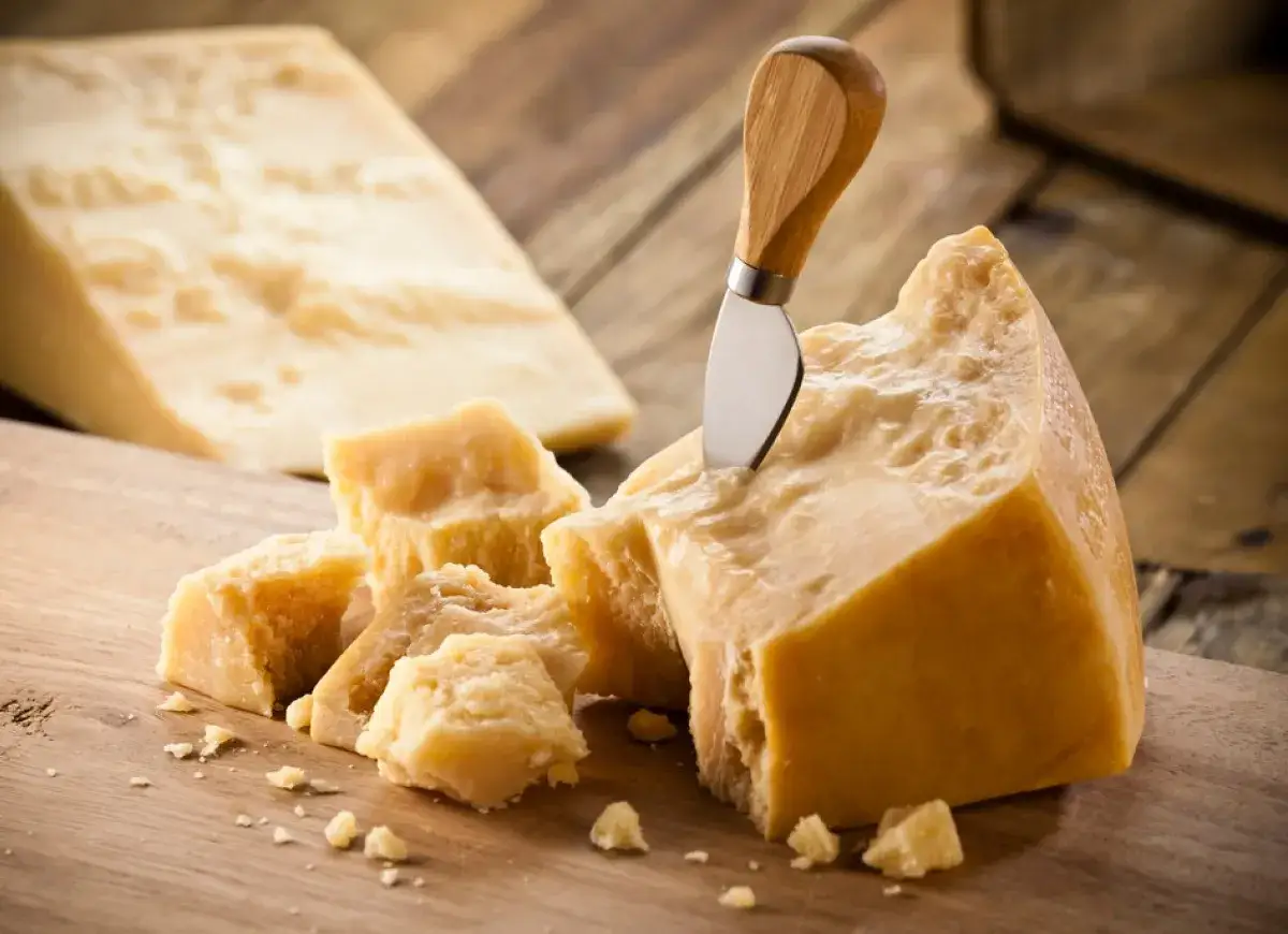 Kawałki Grana Padano i parmezanu, jeden z nich z nożem.