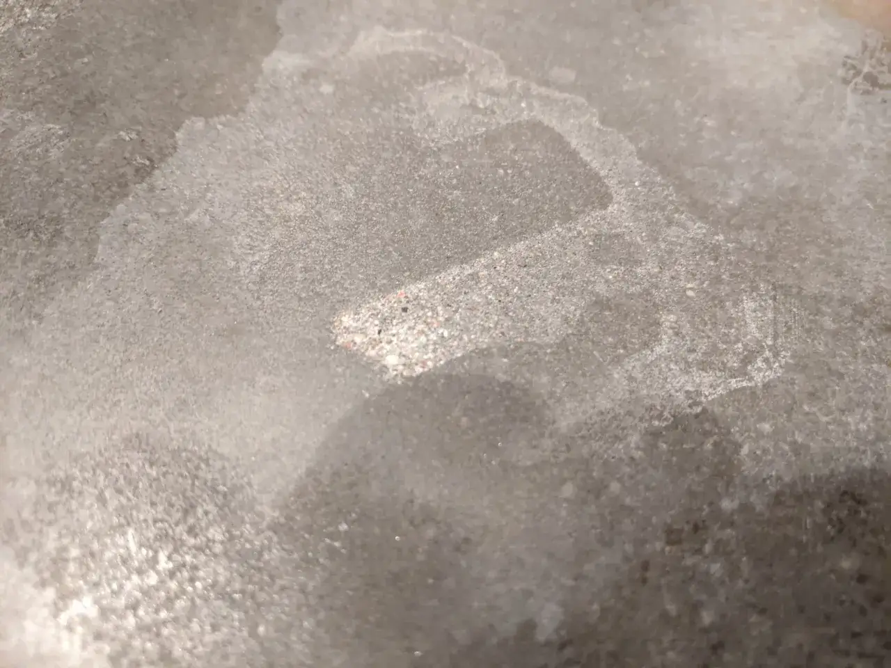 Detaljerad bild av en betongskiva som visar dess textur och nyanser. Ytan är ojämn, med synliga korn och fläckar, vilket ger en känsla av att man ska behandla betongskiva.