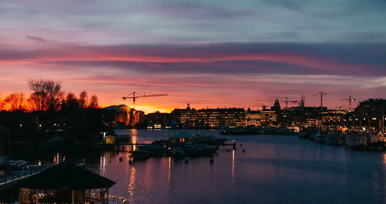 En dramatisk solnedgång över Stockholm, med silhuetter av byggnader, båtar och kranar. En riktigt tricky Stockholm-vy.