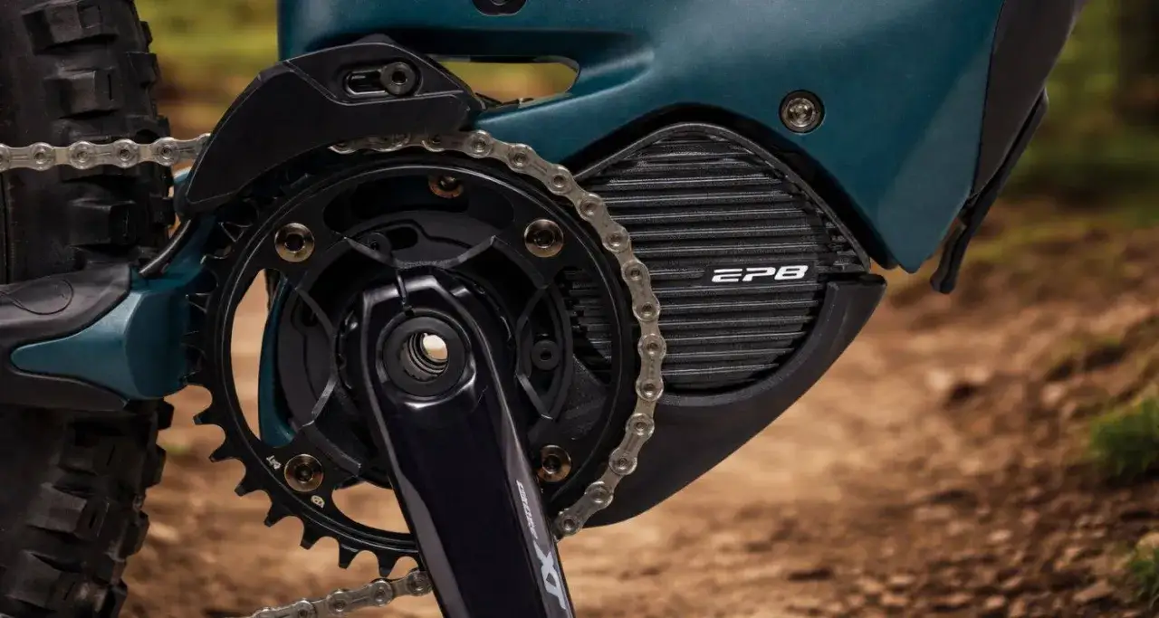 Close-up van de aandrijflijn van een e-bike met Shimano STEPS motor. De ketting loopt over de tandwielen en de motorbehuizing met EP8-logo.