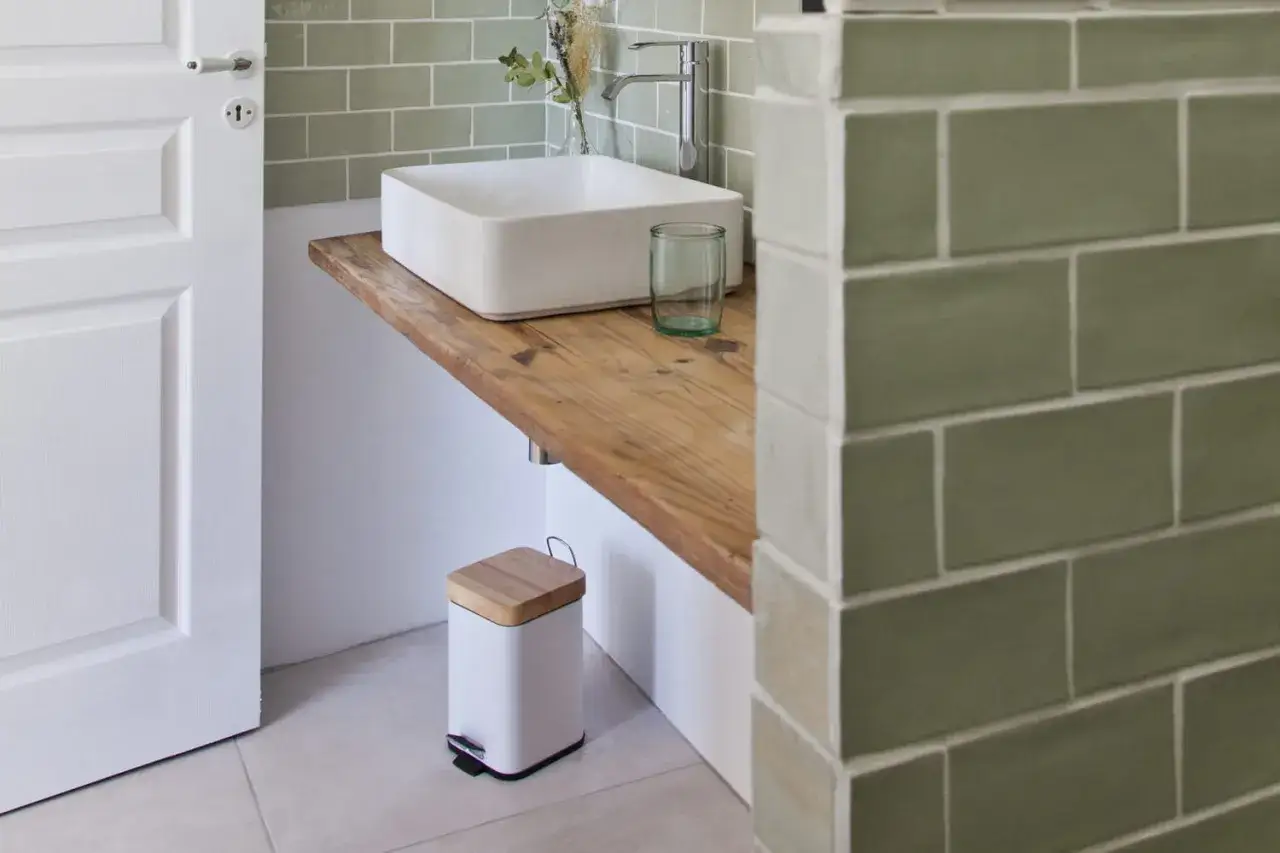 Plan de travail pour salle de bain avec lavabo carré, robinetterie moderne et poubelle design.