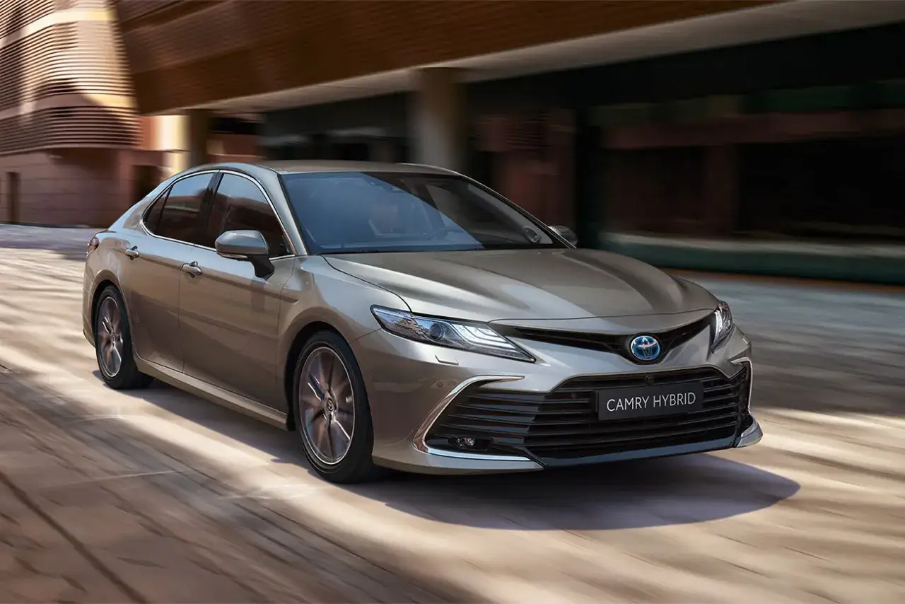 Elegancka, brązowa Toyota Camry Hybrid 2025 pędzi ulicą. Sprawdź jej atrakcyjną cenę!
