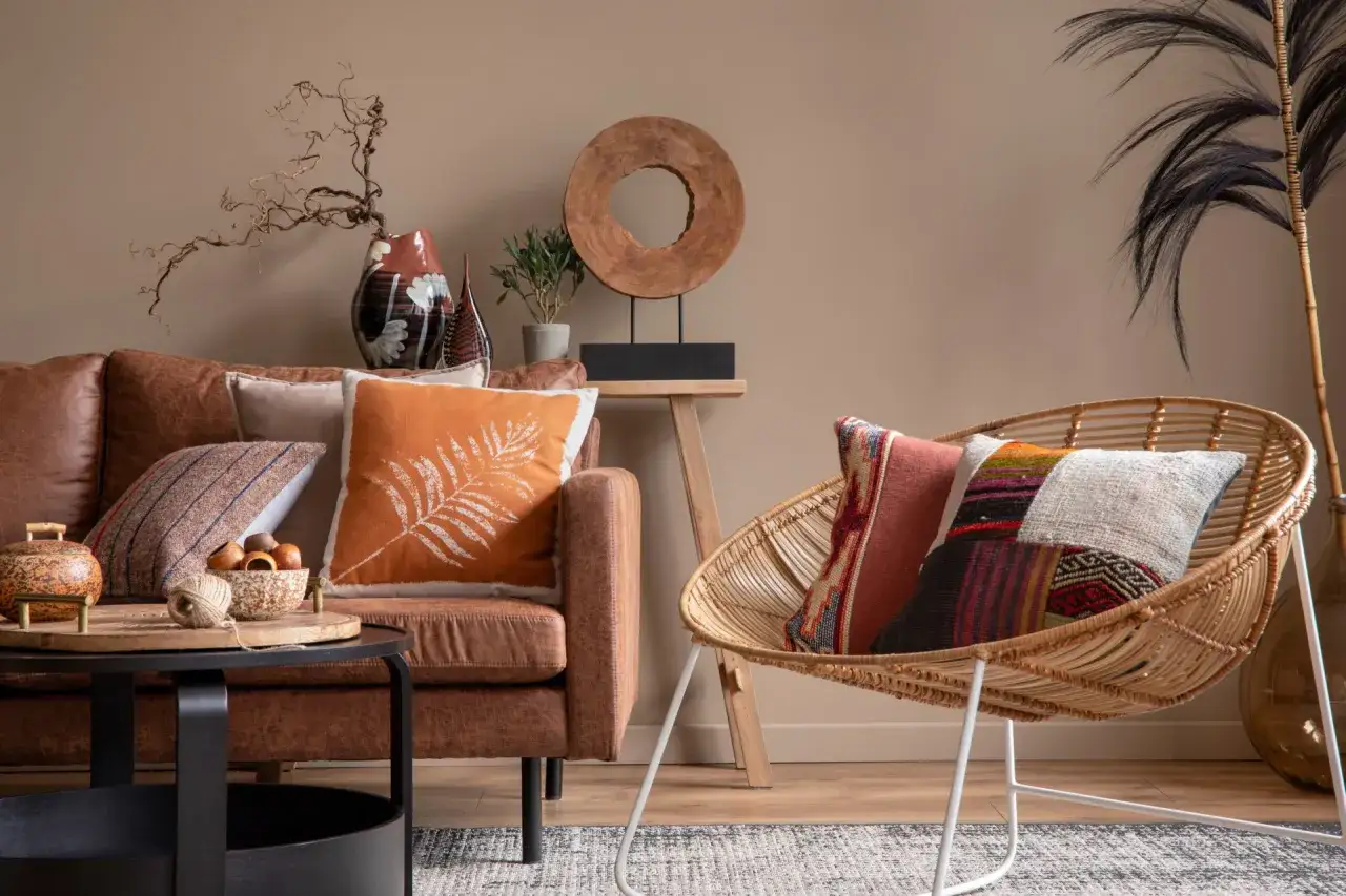 Salon chaleureux avec canapé en cuir marron, coussins colorés et fauteuil en rotin. Une belle idee deco interieur pour un espace cosy.