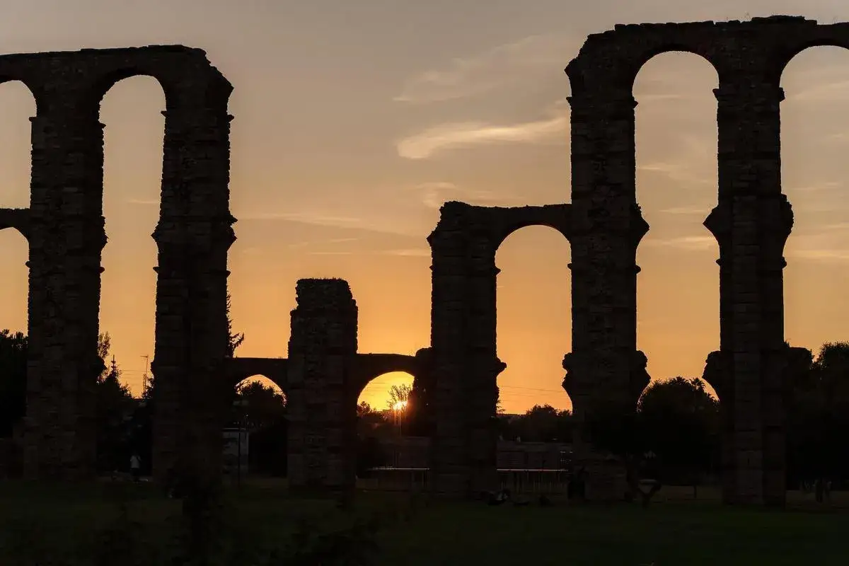 Atardecer en el Acueducto de los Milagros, un imprescindible que ver en Mérida. Siluetas romanas contra el cielo anaranjado.