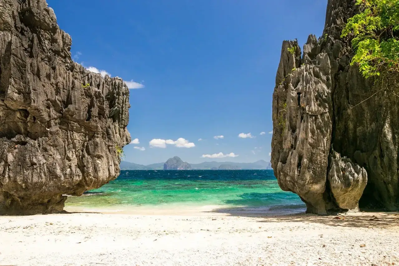 En vit sandstrand med turkost vatten och dramatiska klippformationer p&aring; Palawan, Filippinerna.