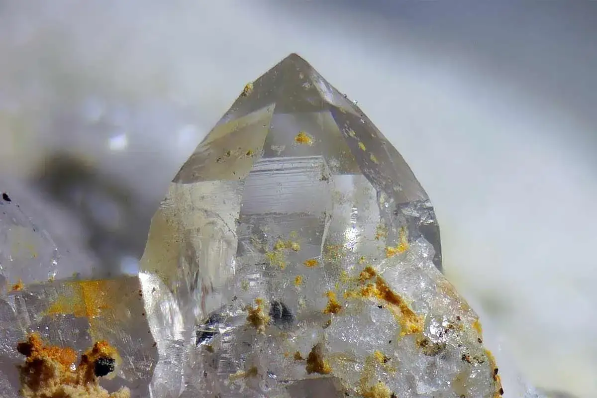 Nahaufnahme eines Bergkristalls mit gelben Einschlüssen, die seine einzigartigen bergkristall eigenschaften unterstreichen.