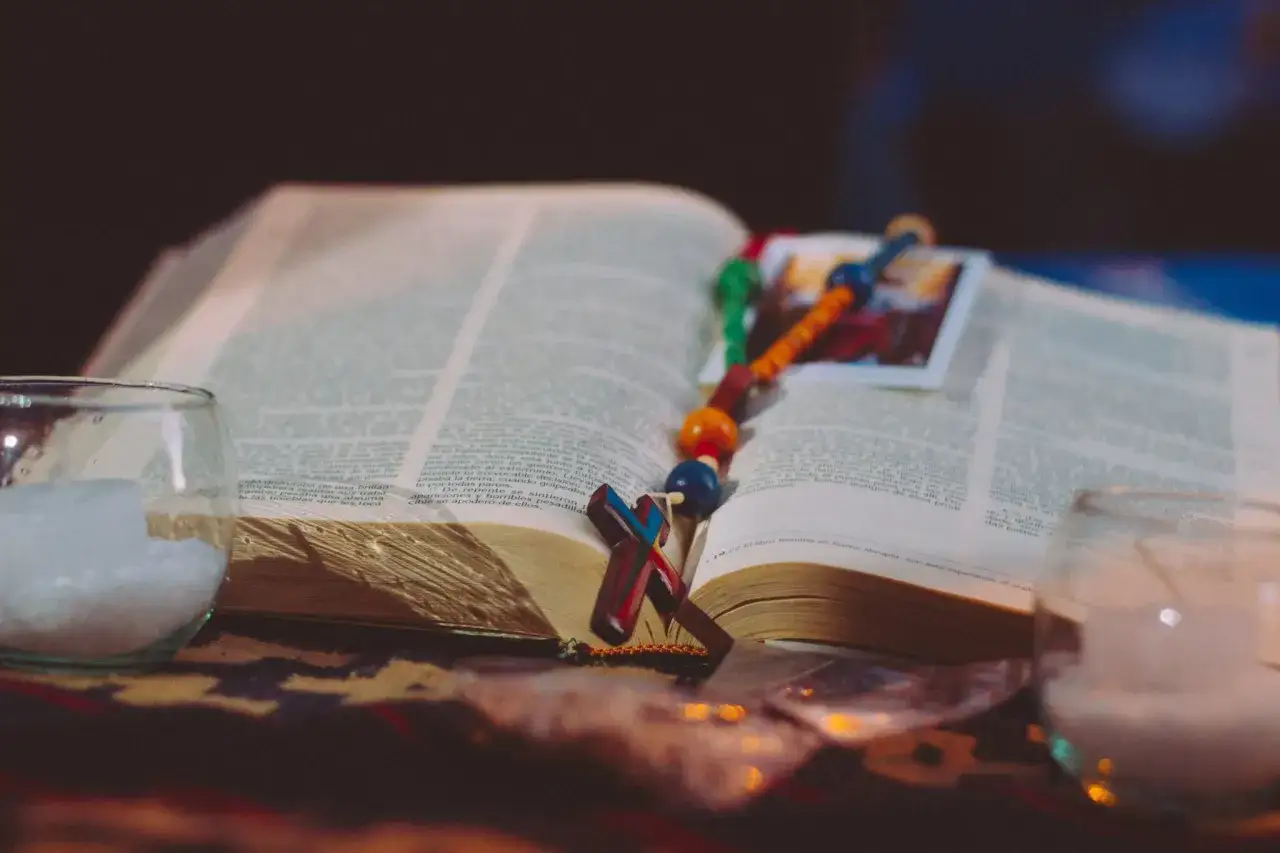 Otwarta Biblia z r&oacute;żańcem i krzyżem, świece. Tekst psalm 131.