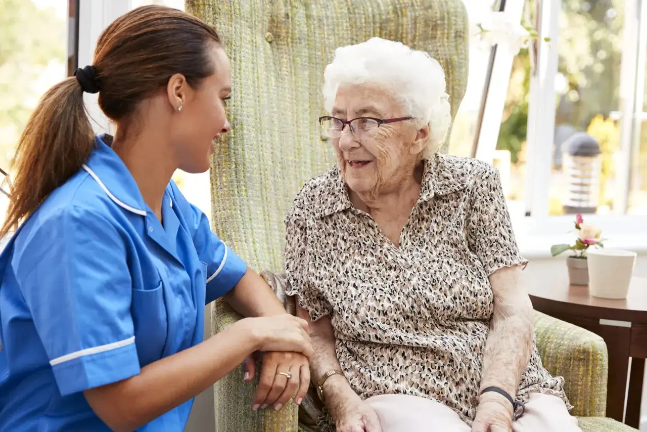 Pielęgniarka rozmawia z seniorką, która może mieć chorobę Alzheimera. Dbałość i wsparcie są kluczowe.