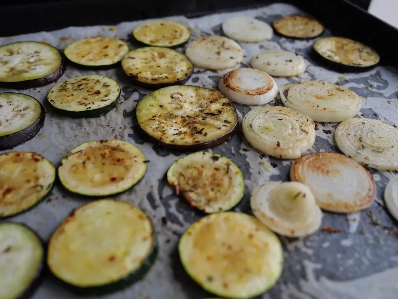 Rondes d'aubergines et de courgettes, assaisonnées et prêtes pour la plancha. Des oignons grillés complètent ce plat de légumes savoureux.