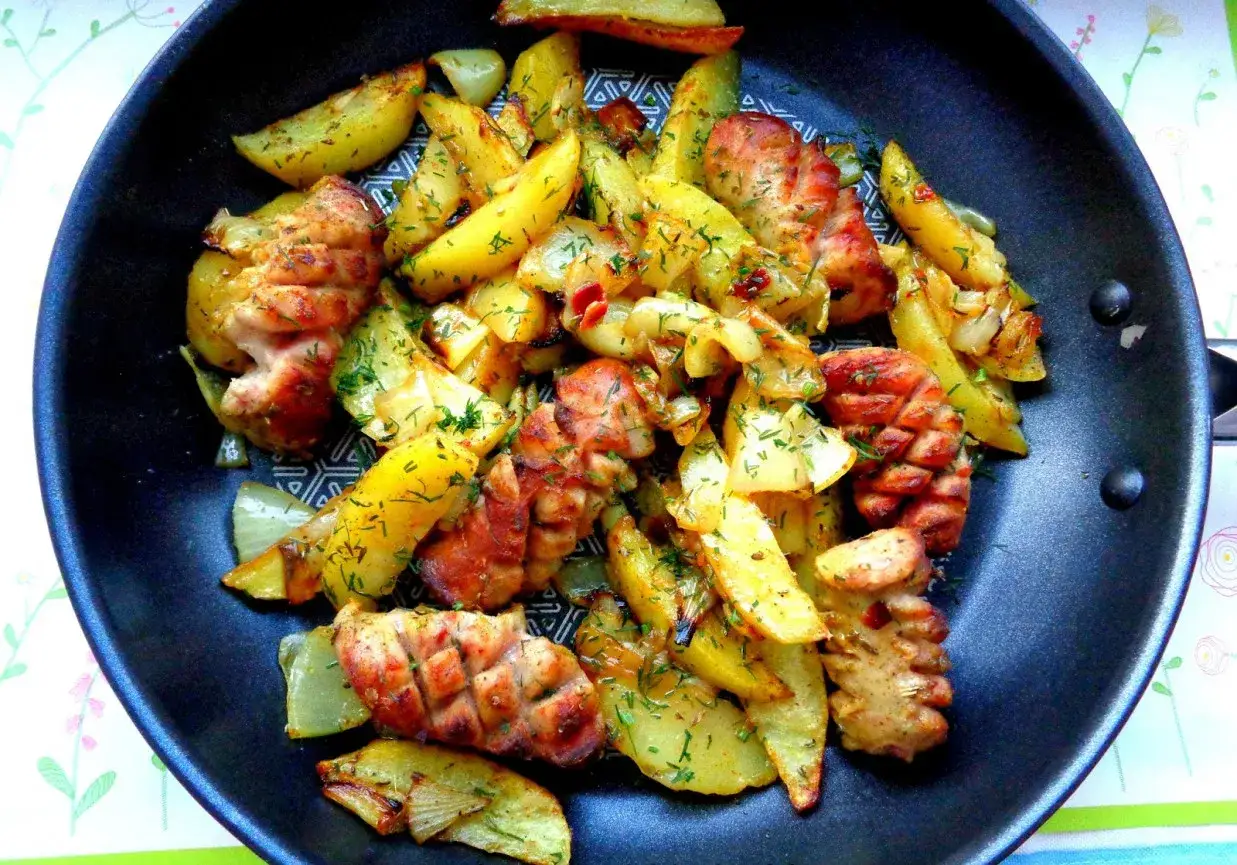 Na patelni pieczona biała kiełbasa z ziemniakami i koperkiem.