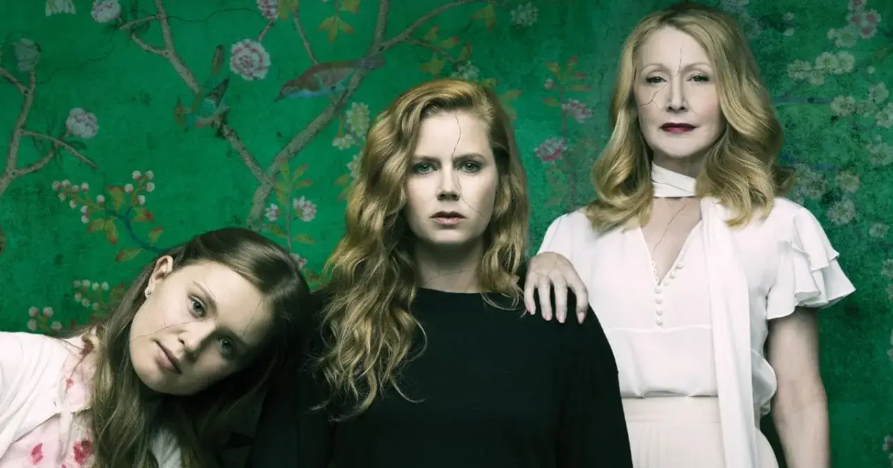 Ostre przedmioty obsada: Amy Adams, Patricia Clarkson i Eliza Scanlen na tle zielonej tapety z ptakami i kwiatami.