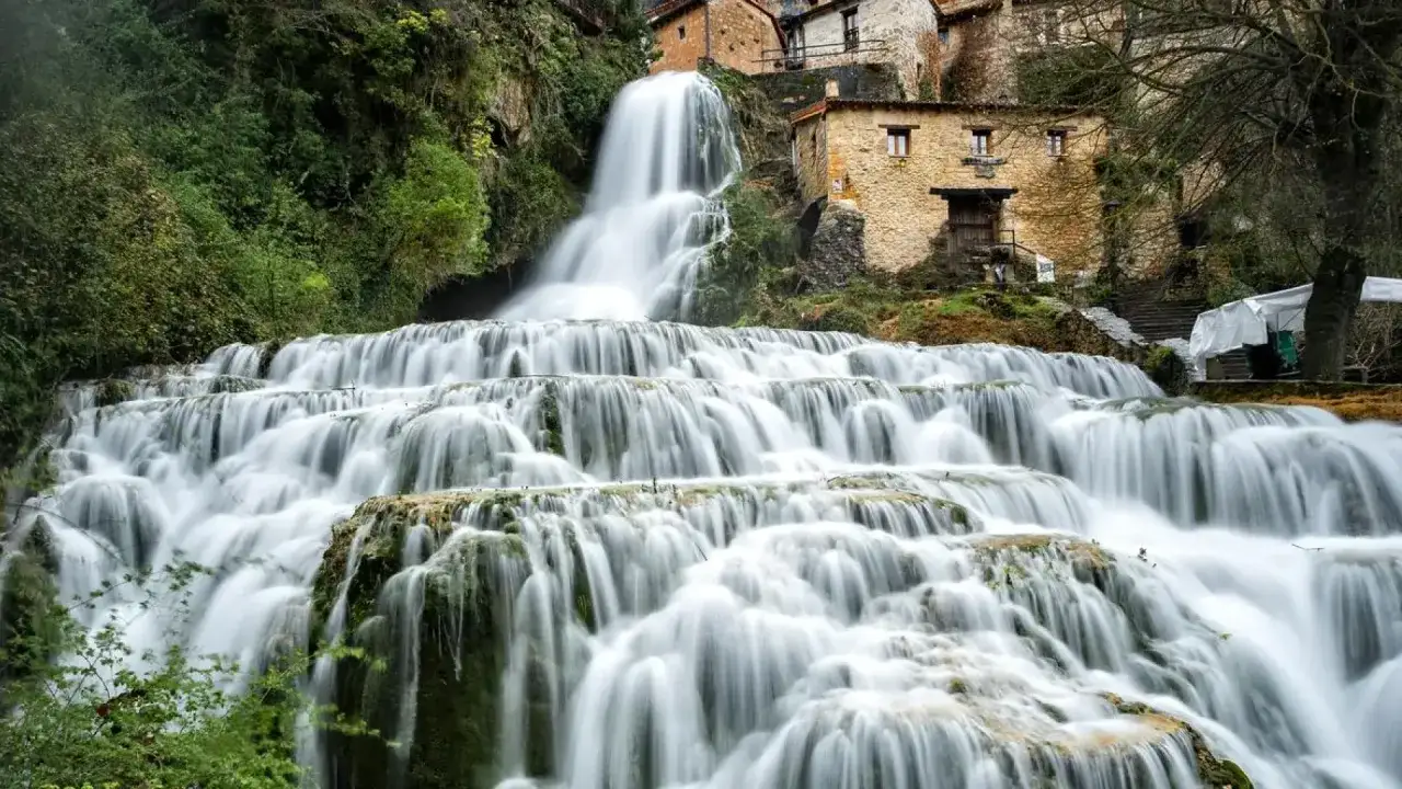 Cascada en cascada con casas de piedra integradas en la ladera, parte de las **rutas Burgos**.