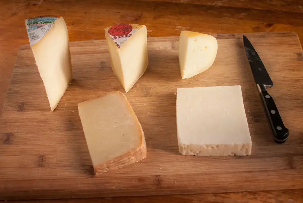 Fem olika ostar, inklusive pecorino ost, ligger upplagda p&aring; en tr&auml;sk&auml;rbr&auml;da bredvid en kniv.