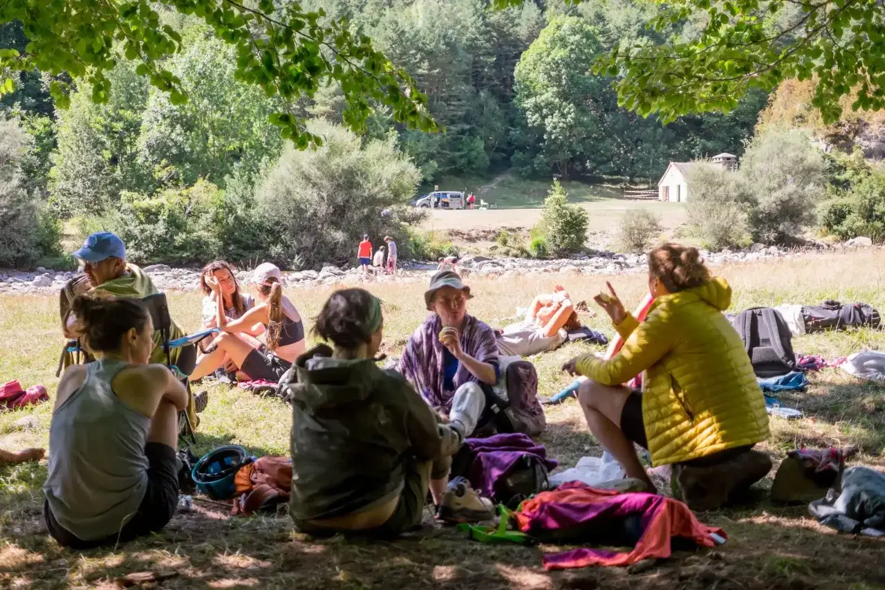 Grupo de amigos descansando en la naturaleza, disfrutando de un día soleado. Una experiencia perfecta para quienes disfrutan viajar sola.