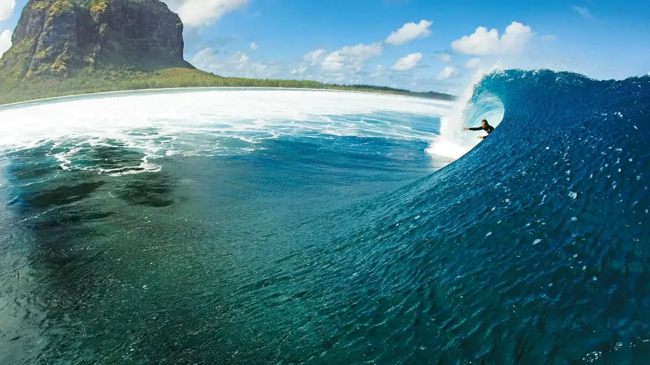 Surfer reitet eine perfekte Welle vor der K&uuml;ste von Mauritius. Der Berg Le Morne im Hintergrund.