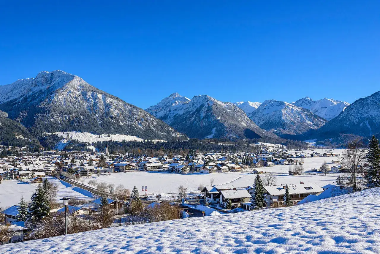 Schneebedeckte Berge und ein verschneites Dorf im Dezember in Deutschland. Ein idyllischer Anblick, wo liegt schnee im dezember in deutschland?