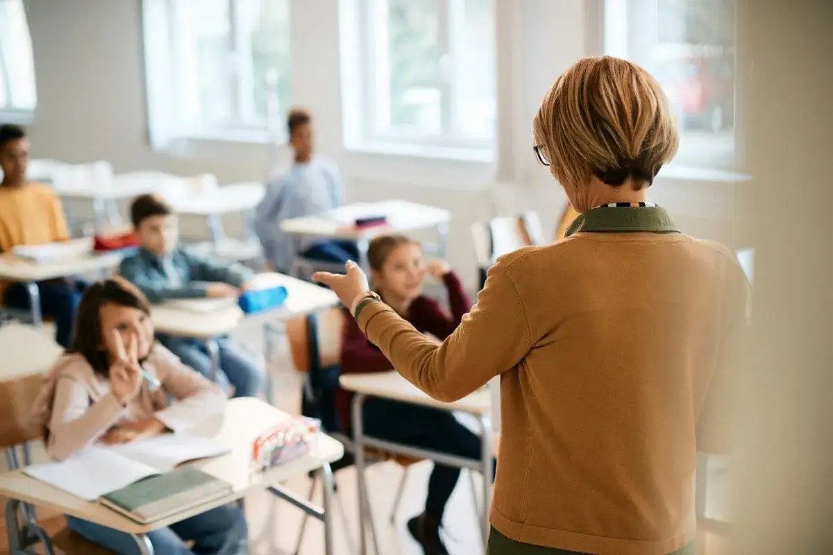 Nauczycielka tłumaczy lekcję, a uczniowie słuchają. Ile godzin pracy to etat nauczyciela?
