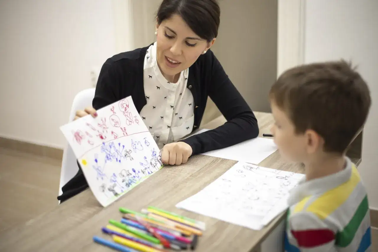 Psicologa analizza disegni di un bambino, un supporto per affrontare la psicosi infantile.