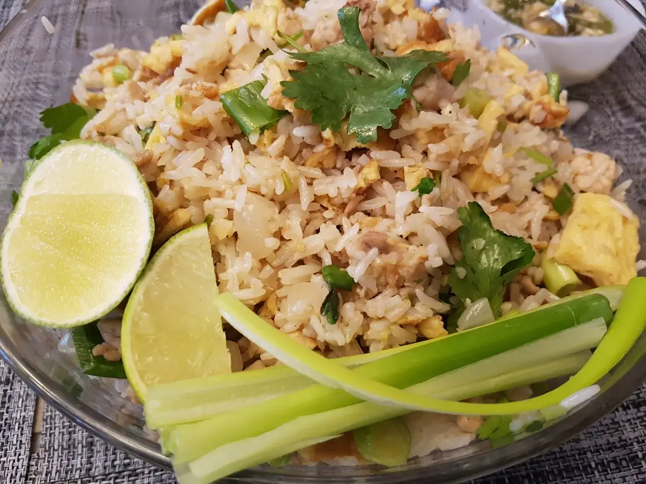En skål med khao pad, en thailändsk stekt risrätt, med ägg, gröna lökar, koriander och limeklyftor.