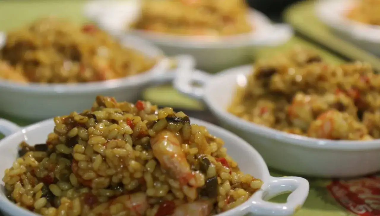 Delicioso arroz con gambas y verduras, servido en varios cuencos blancos, listo para disfrutar.
