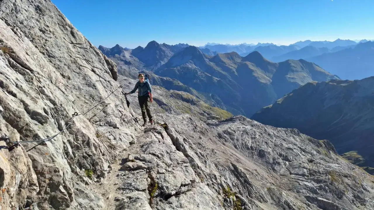 Wanderer auf der Heilbronner Weg Route, gesichert an einem Stahlseil, genie&szlig;t die atemberaubende Berglandschaft.
