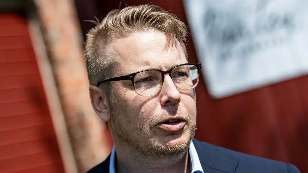 Fredrik Backman, med glasögon och skäggstubb, pratar framför en röd vägg. Kanske ett inlägg på hans fredrik backman blogg?