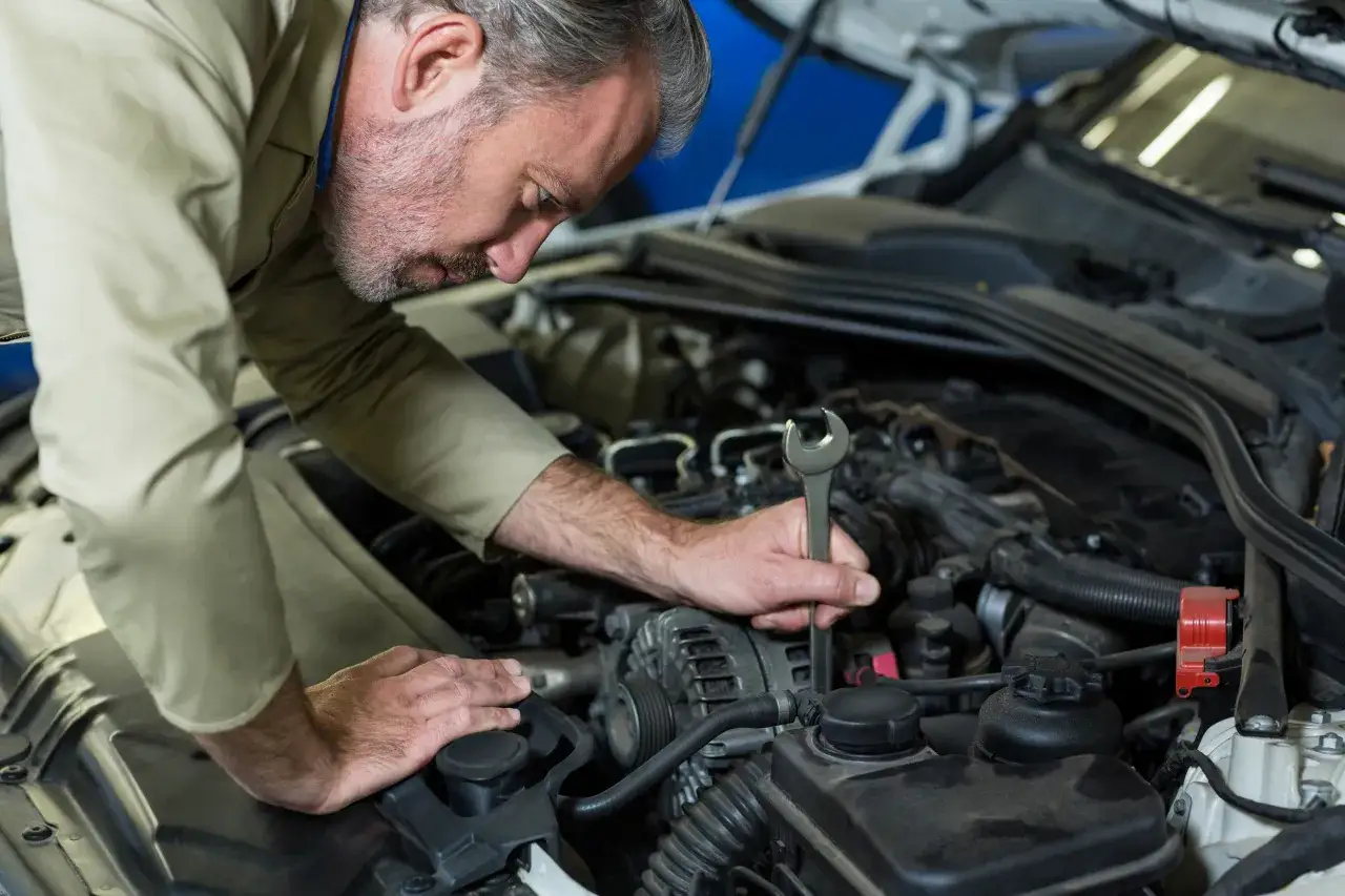 Mechanik naprawia silnik, szukając przyczyny nagłego braku wspomagania kierownicy.