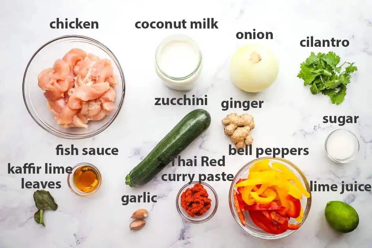 Zutaten für ein rotes Thai Curry: Hähnchen, Kokosmilch, Zucchini, Paprika, Ingwer, Knoblauch, Kaffirlimettenblätter, Fischsauce, Limettensaft, Zucker, Zwiebel und Koriander.