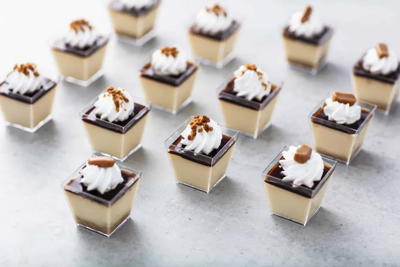 Små, eleganta pannacotta-desserter i plastglas, toppade med grädde och krossade kex eller karamell. Perfekt som dessertvin till pannacotta.