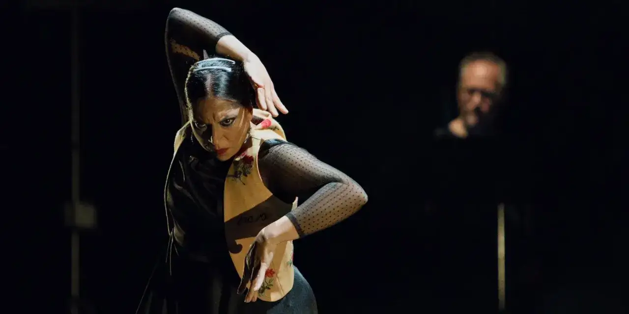 Fuensanta la Moneta, bailaora de flamenco, en un momento de intensa expresi&oacute;n. Un hombre borroso al fondo.