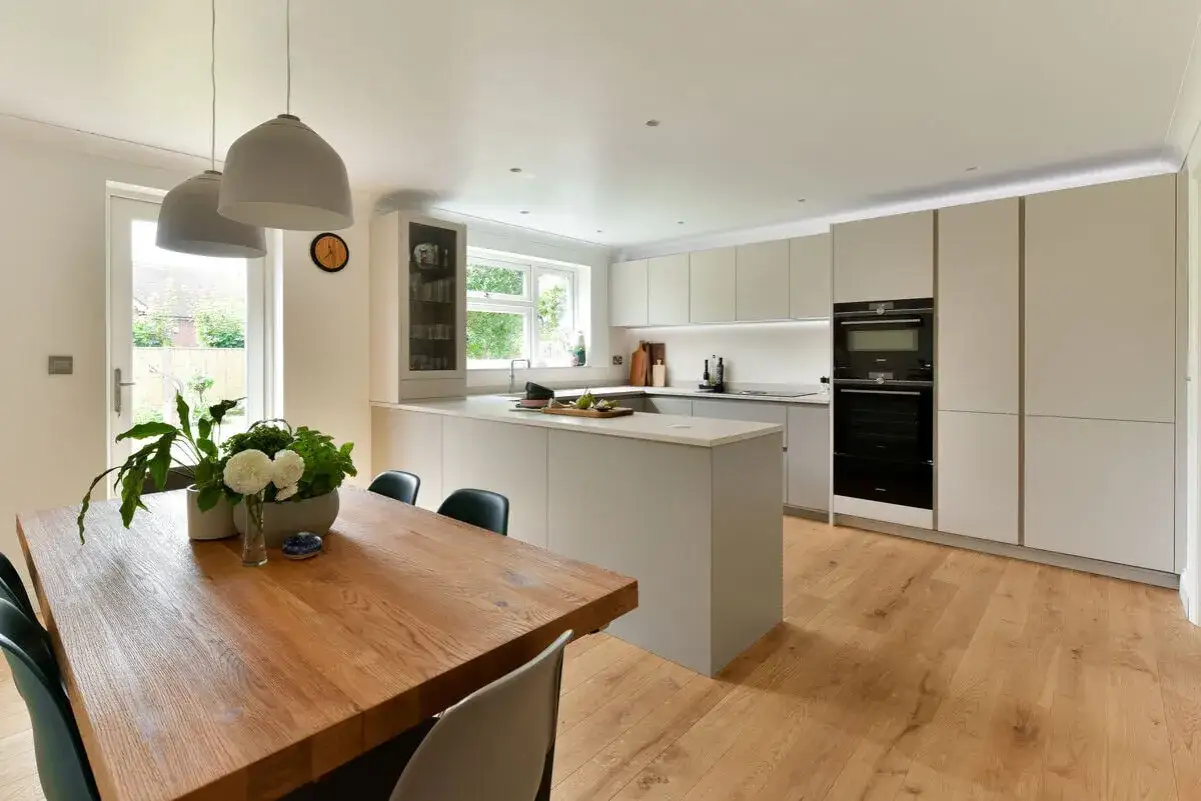 A modern kitchen with a large wooden breakfast table, perfect for family meals. The table's generous breakfast table dimensions suggest ample space for everyone.