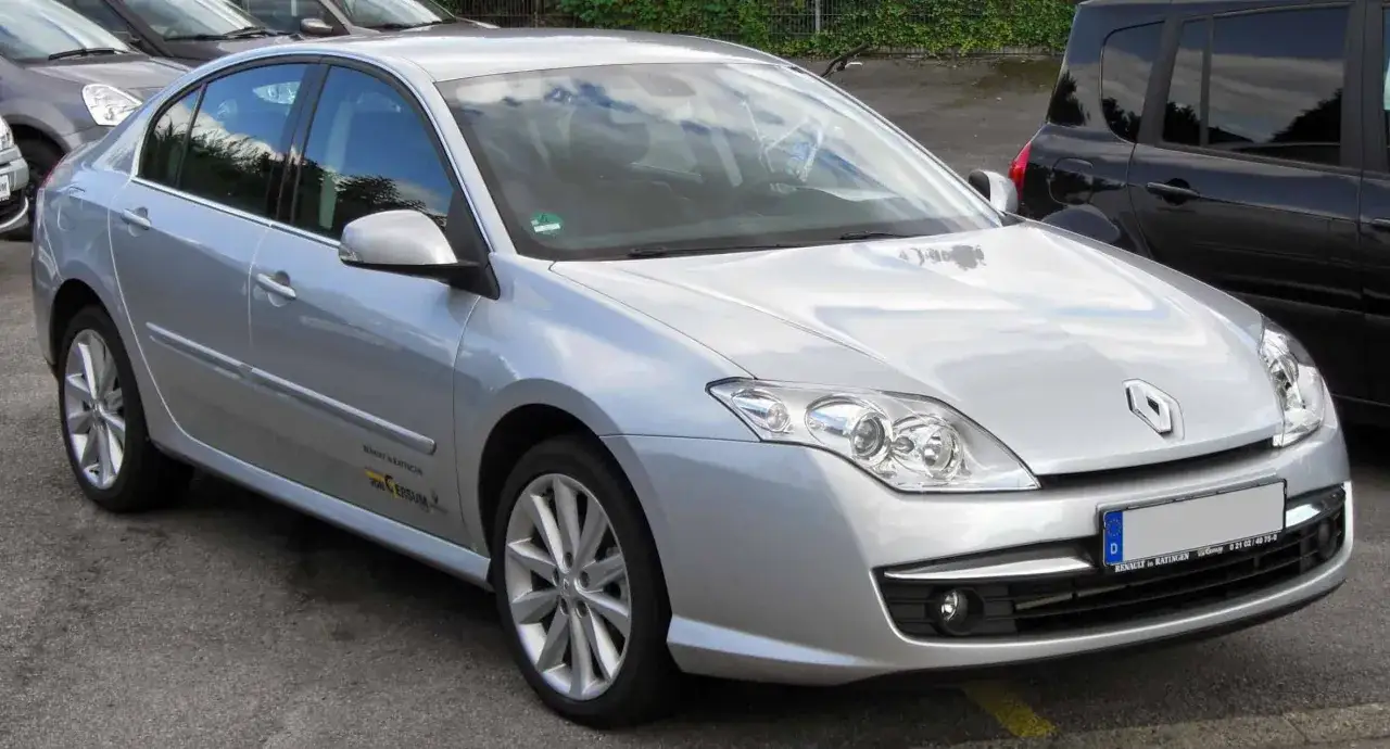 Srebrny sedan Renault Laguna 3 2.0 benzyna zaparkowany obok czarnego SUV-a.