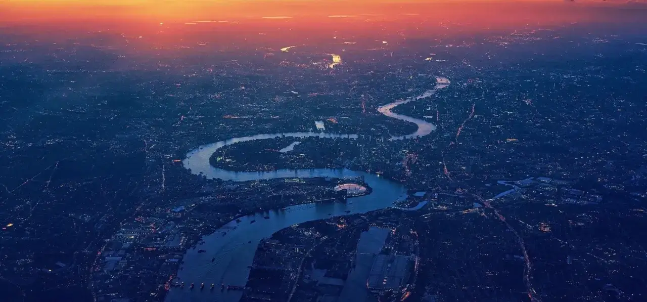 Widok z lotu ptaka na Tamizę o zachodzie słońca, oświetlony Londyn. Ta panorama miasta to żywa historia.