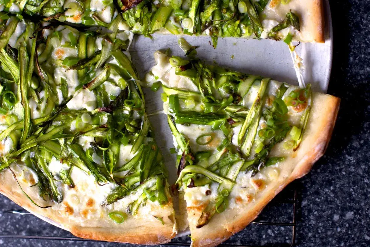 Pyszna pizza ze szparagami i ciągnącym się serem, posypana szczypiorkiem. Idealna na wiosenny obiad.